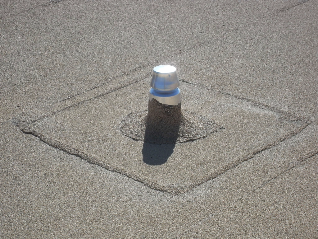 Vent pipe and flashing patch on a granule-surfaced flat roof